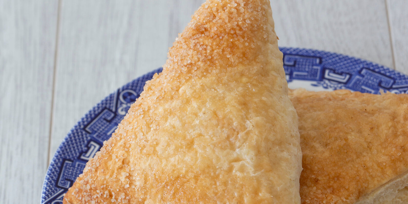 Apple turnover on a blue and white plate with a grey wood backgr