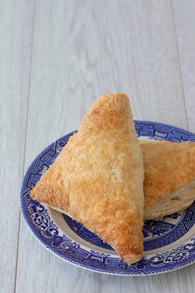 Apple turnover on a blue and white plate with a grey wood backgr