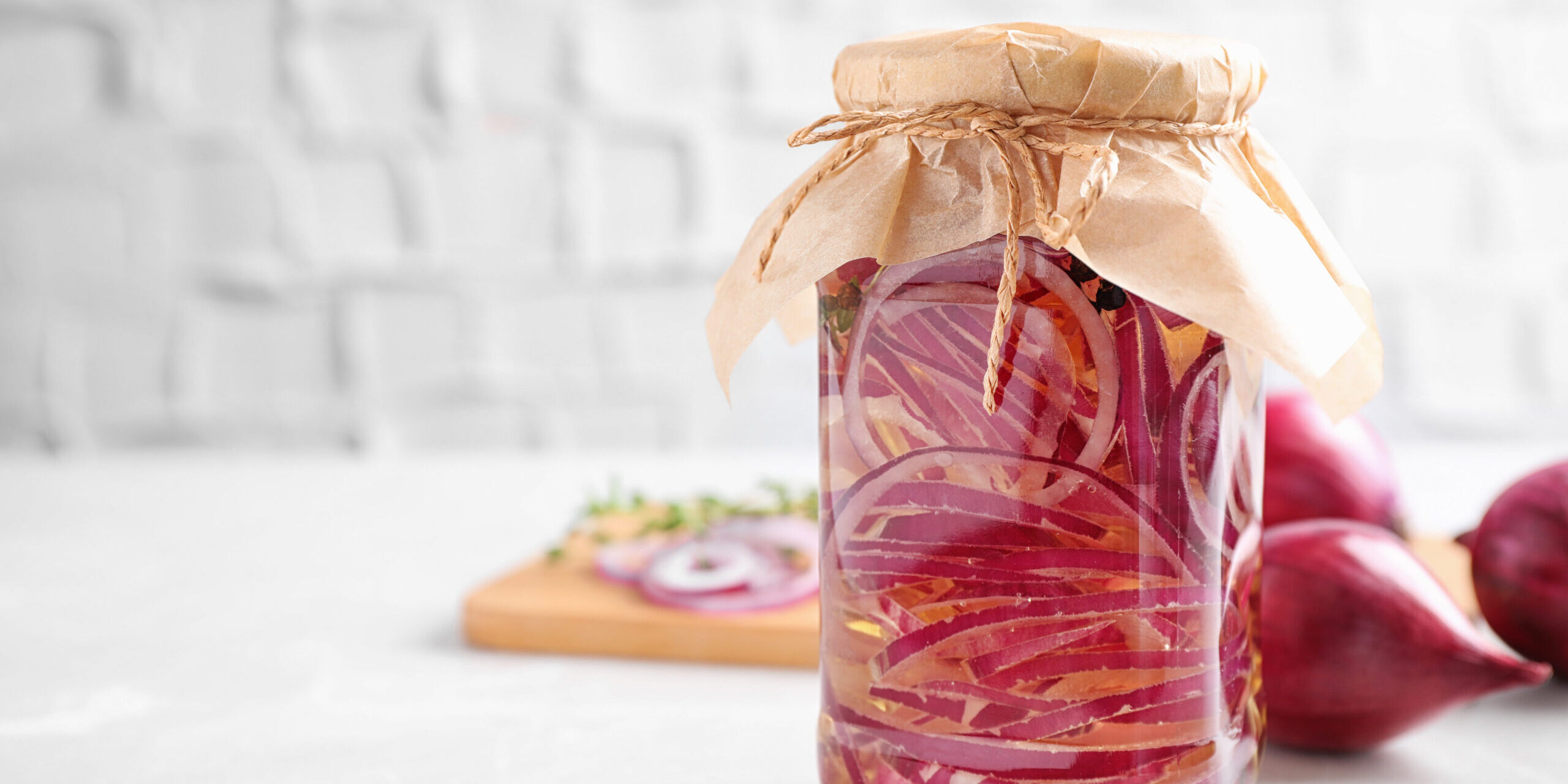 Jar of pickled onions on white table. Space for text