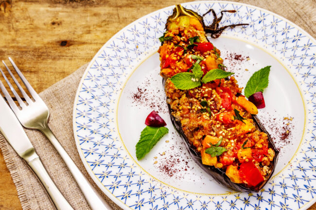 Karniyarik traditional Turkish food from stuffed eggplants with minced meat, tomato, greens and sesame seeds